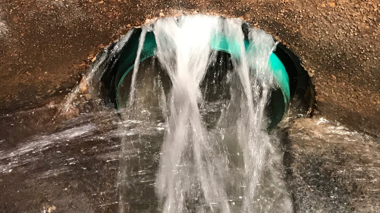Active groundwater infiltration pouring through a pipe penetration in a concrete structure before injection grouting