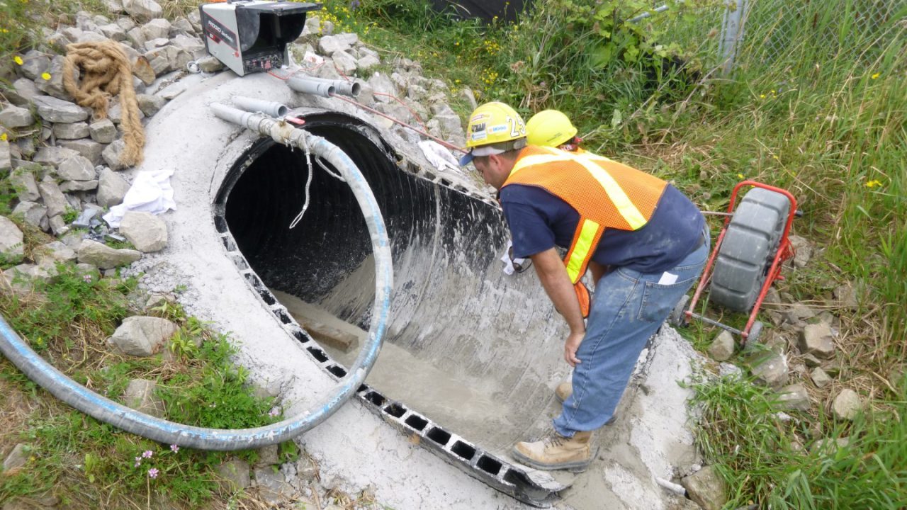 Worker completing the bulkhead at a sliplined culvert end during annular grouting