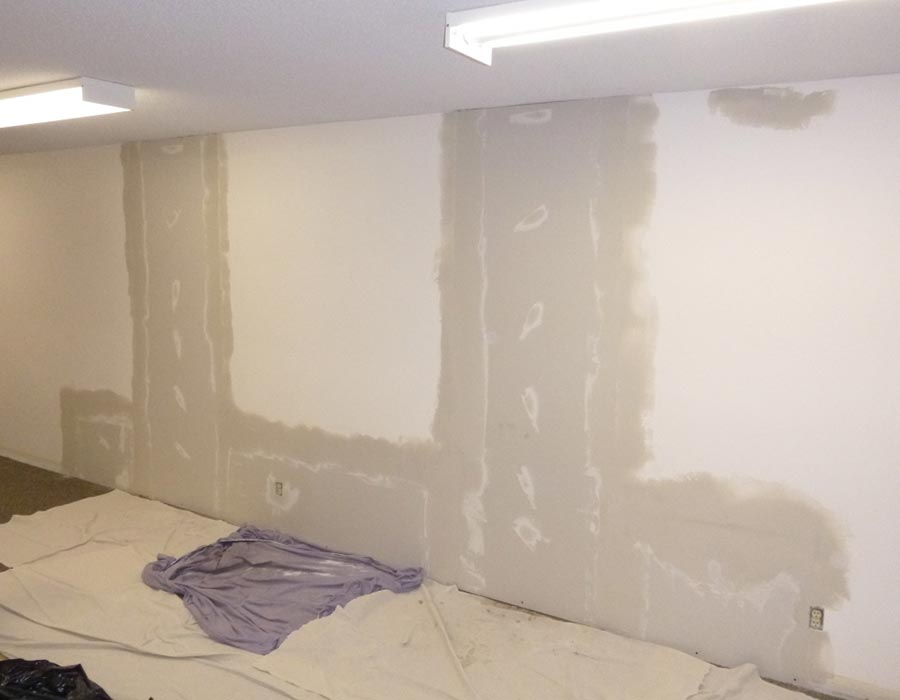 Before: leaking cracks in a poured concrete basement foundation wall with the finishes removed