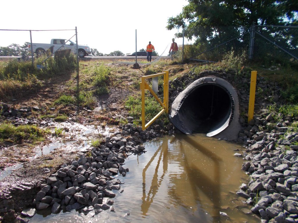 Relined culvert outlet discharging into a watercourse beside a highway