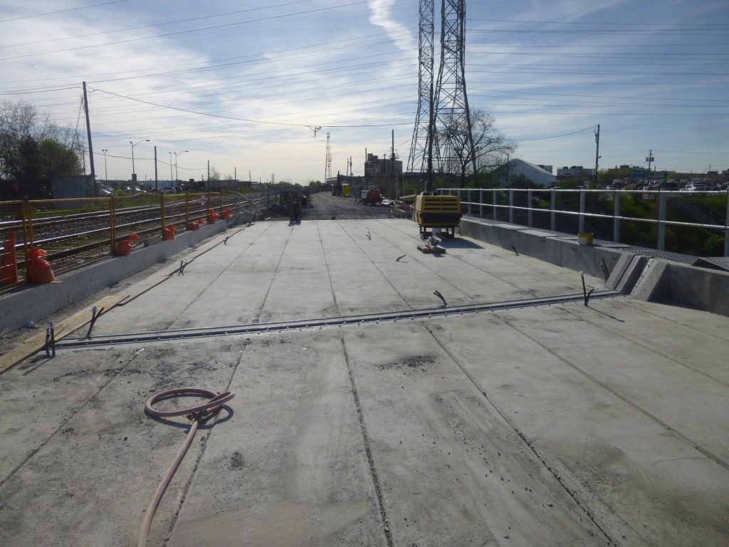 Grout delivery lines laid along the bridge deck toward the girder joints