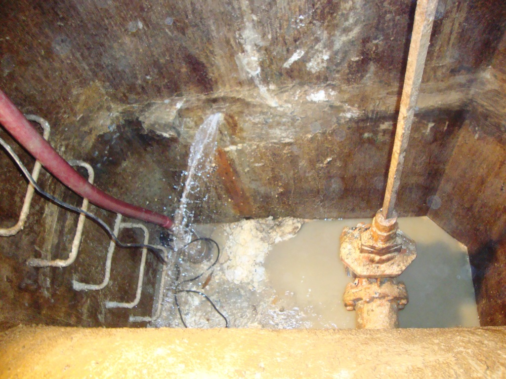 Groundwater pouring into a municipal valve chamber through the wall and pipe penetrations before injection grouting