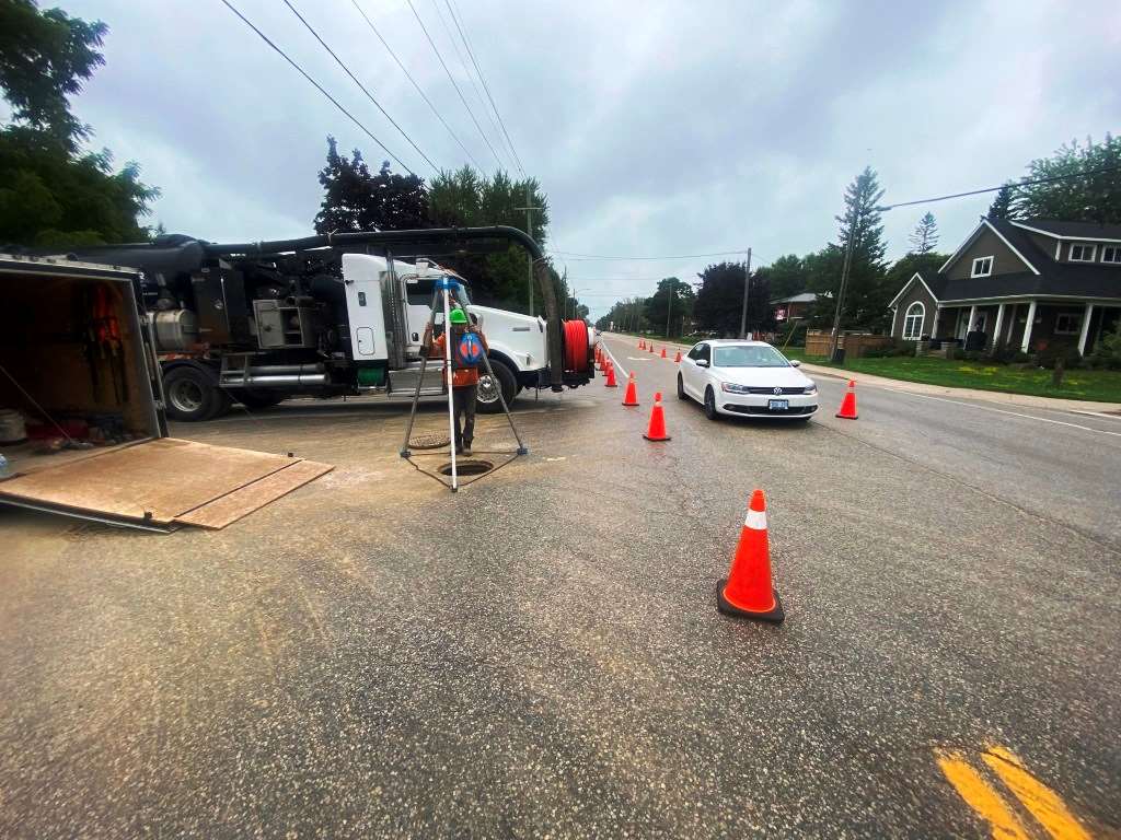 SG Services truck and traffic cones set up over a manhole on a rural road